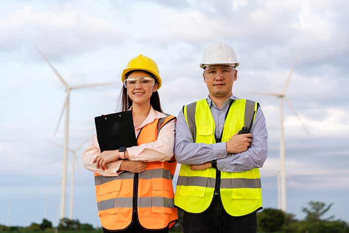 Engineer team working against wind turbine farm