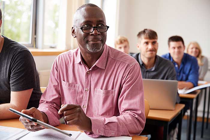 Mature Student Using Digital Tablet In Adult Education Class