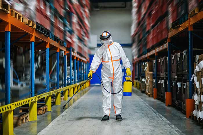 worker with protective mask and suit disinfecting industrial factory with spray gun