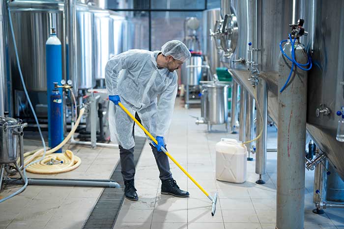 Professional industrial cleaner in protective uniform cleaning floor