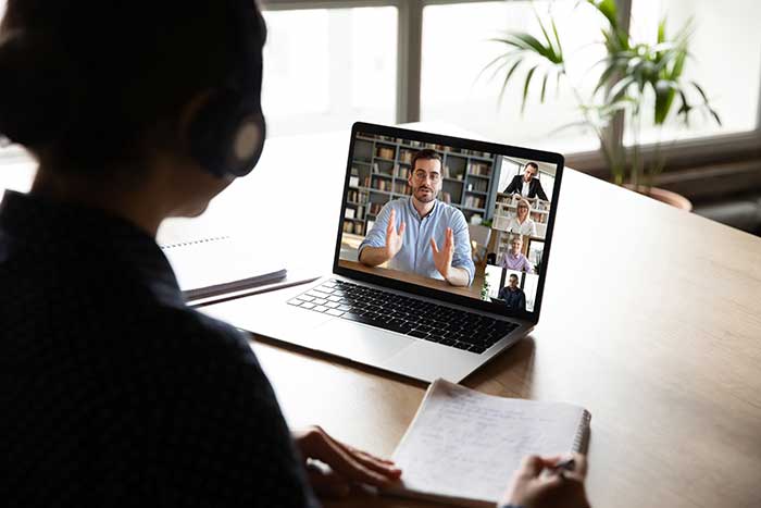 Pc screen view over woman shoulder during group videocall e-learning